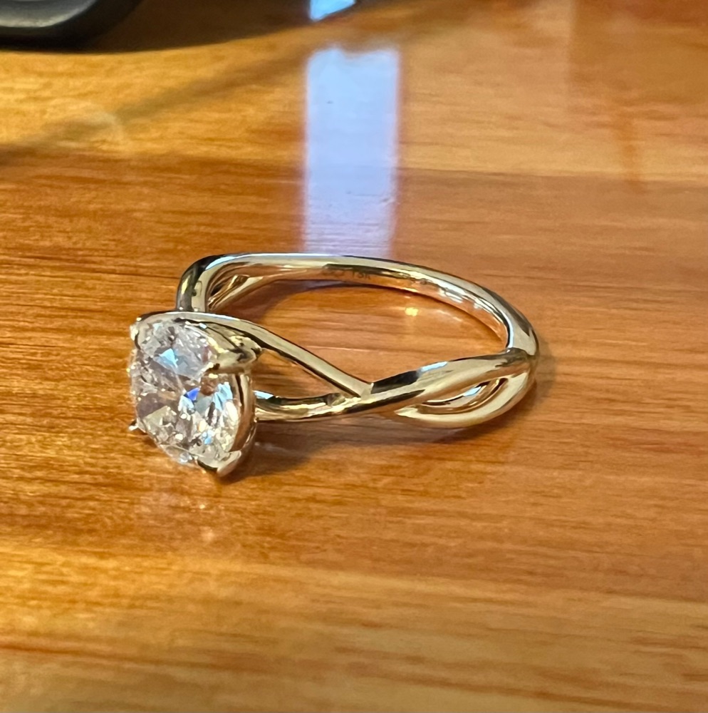 Customer photo of the same yellow gold twist solitaire ring from the side, showing the crossing band